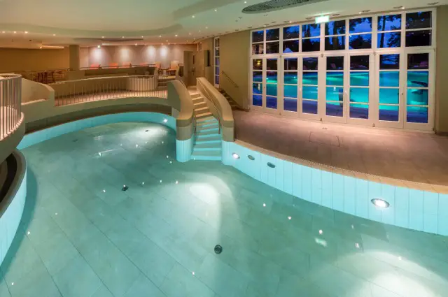Interior view of a luxurious spa area with a lit indoor pool at the Precise Resort Bad Saarow.