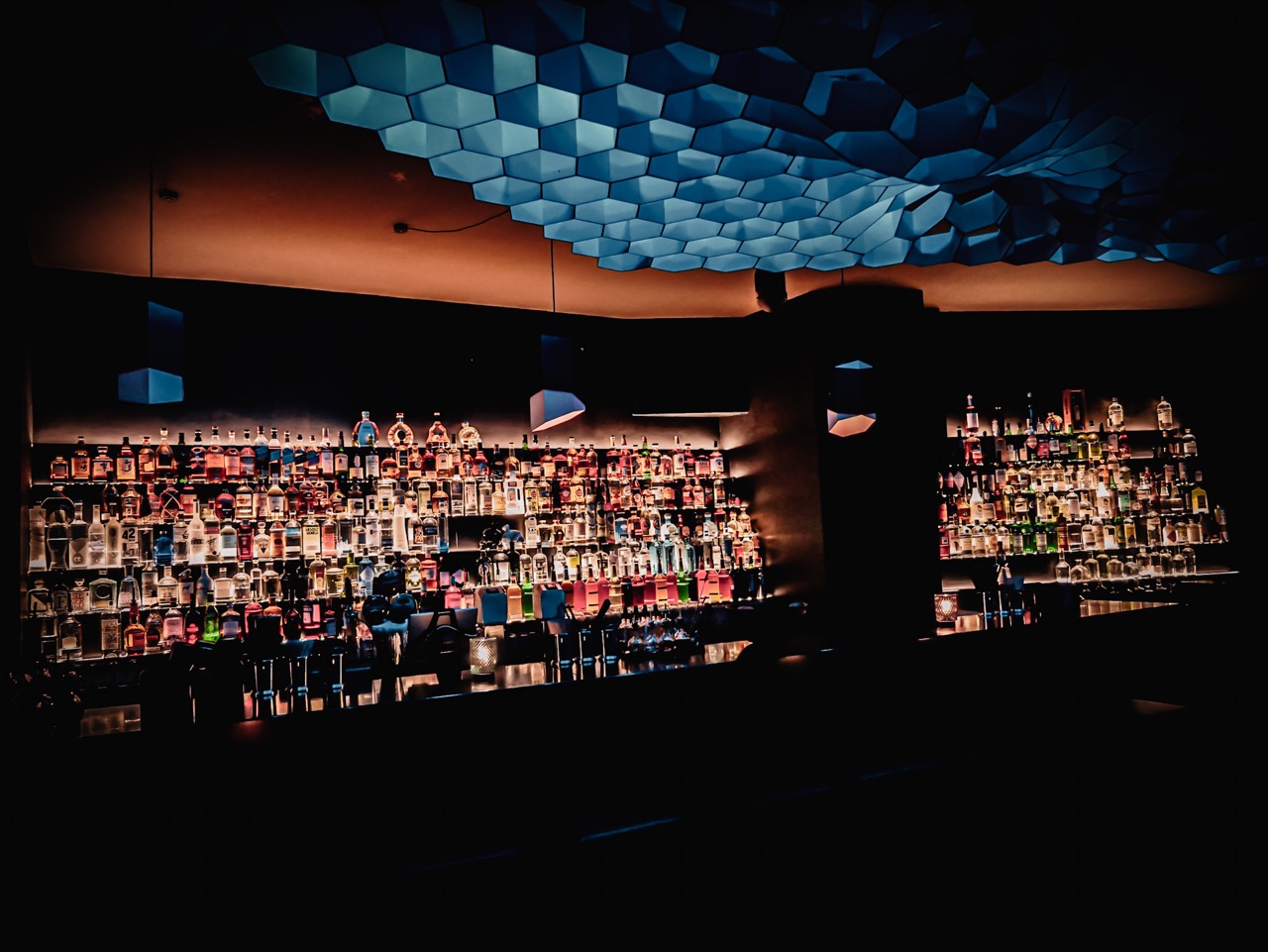 A refreshing cocktail served on a bar coaster at Sharlie Cheen Bar in Berlin Mitte, illuminated by ambient lighting with shadow patterns.