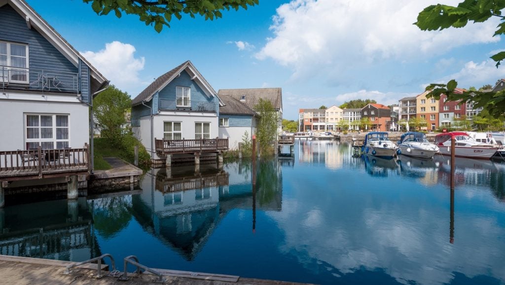 Malerische Hafensiedlung des Precise Resort Marina Wolfsbruch mit farbenfrohen Ferienhäusern entlang des Wassers.