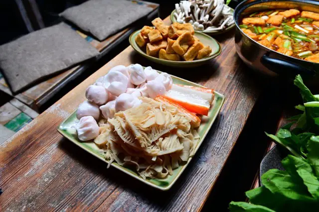 Close-up view of an array of side dishes for an Asian hotpot on a rustic wooden table at Anjoy Restaurant.