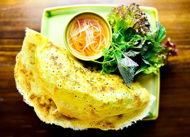 Vietnamesischer Crêpe, serviert mit frischem Salat und einer würzigen Sauce.