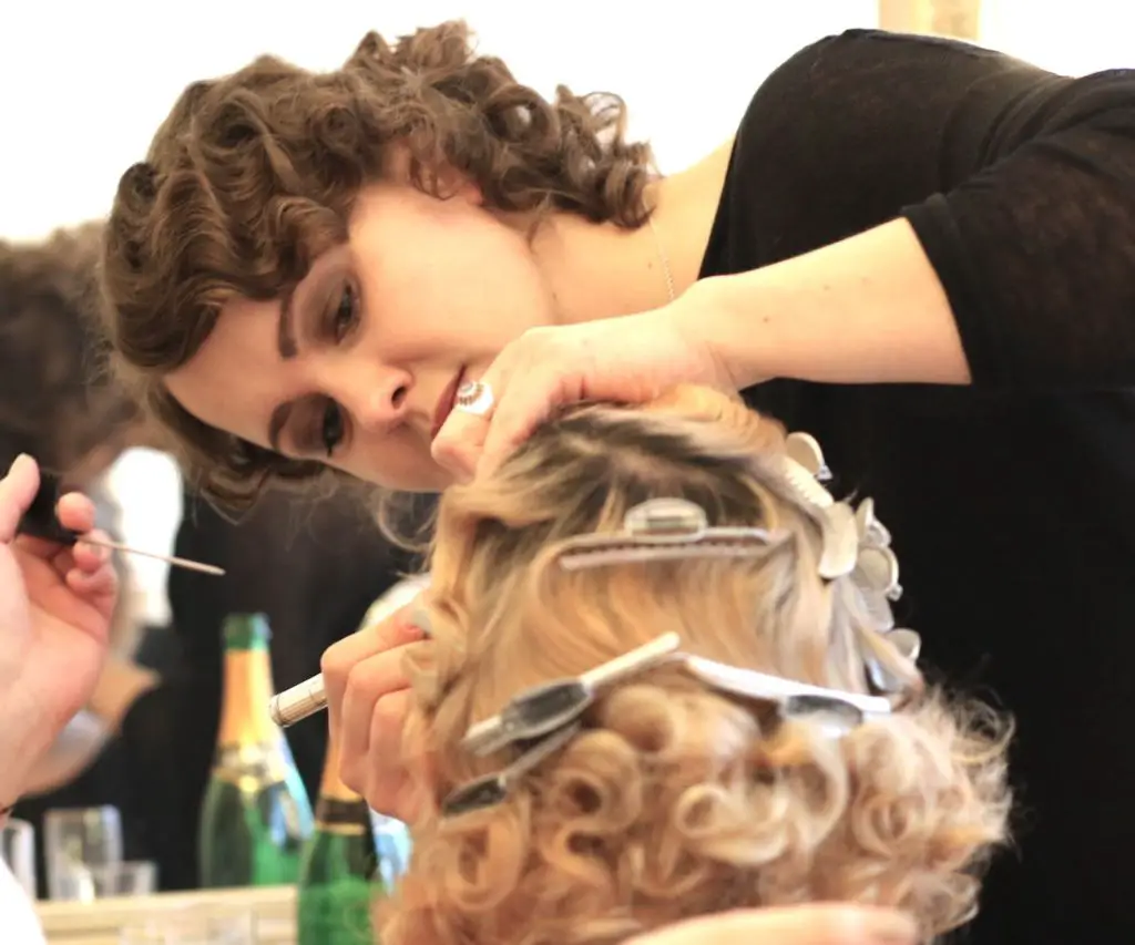 Ein Friseur arbeitet aufmerksam an der Frisur eines Kunden im Püppikram Beauty Salon, mit Haarklammern und Werkzeugen in der Hand.