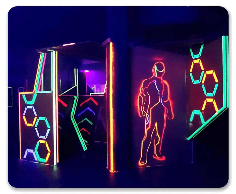 Neonbeleuchtete Lasertag-Arena mit futuristischen Designs und leuchtenden Spieler-Silhouetten an den Wänden.