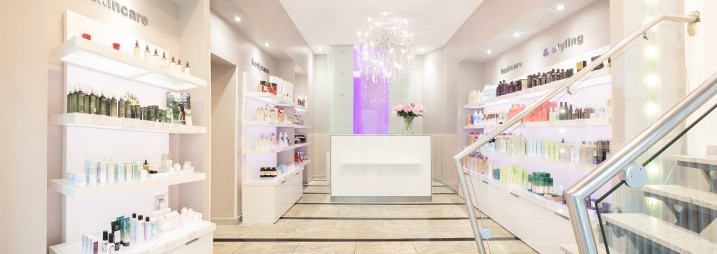 Empfangsbereich von Strauch Friseure in Berlin-Mariendorf mit modernem Design, MacBook und glitzerndem Kronleuchter.