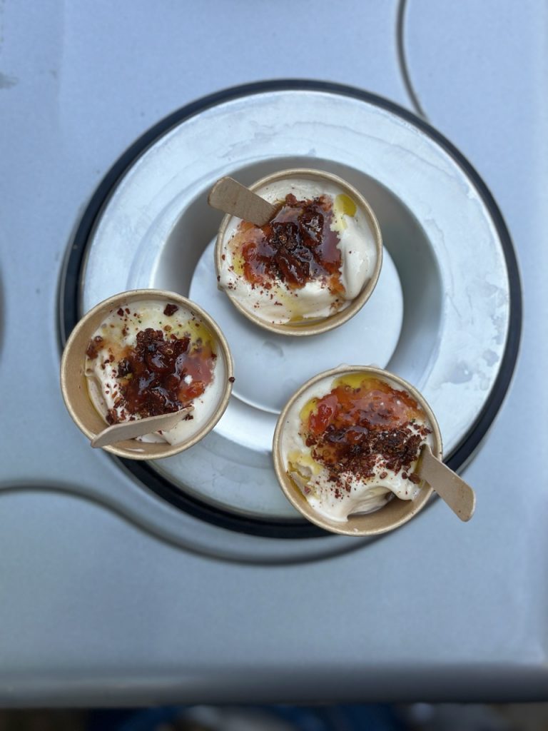 Drei Becher sizilianisches Eis von Duo, mit fruchtiger Sauce, Streuseln & Olivenöl, auf einem Tablett.